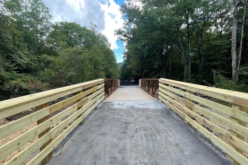 A rail trail with freshly laid gravel crosses a bridge over a creek.