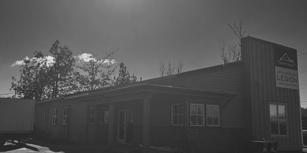 Black and white photo of an American Legion building with surrounding trees.