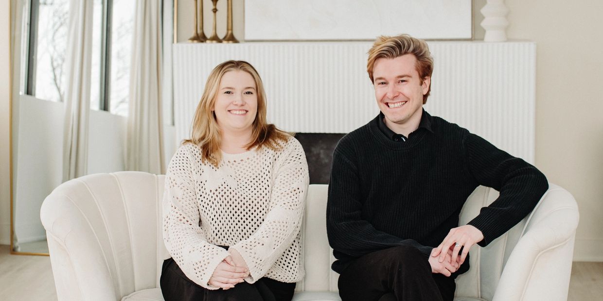 A smiling couple sitting on a white sofa in a bright room.