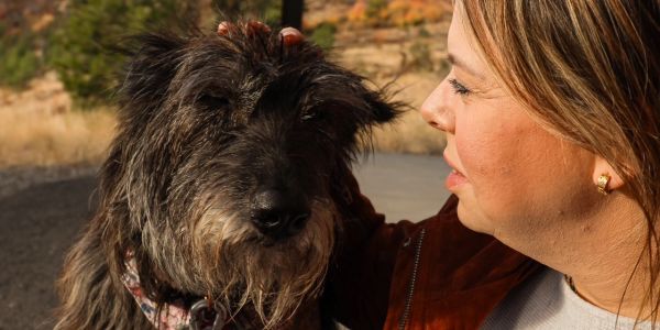 Woman gently petting a large dog outdoors.