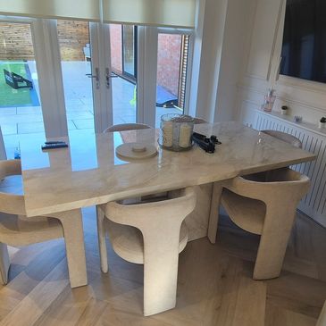 Elegant dining area with a marble table and cushioned chairs near glass doors.