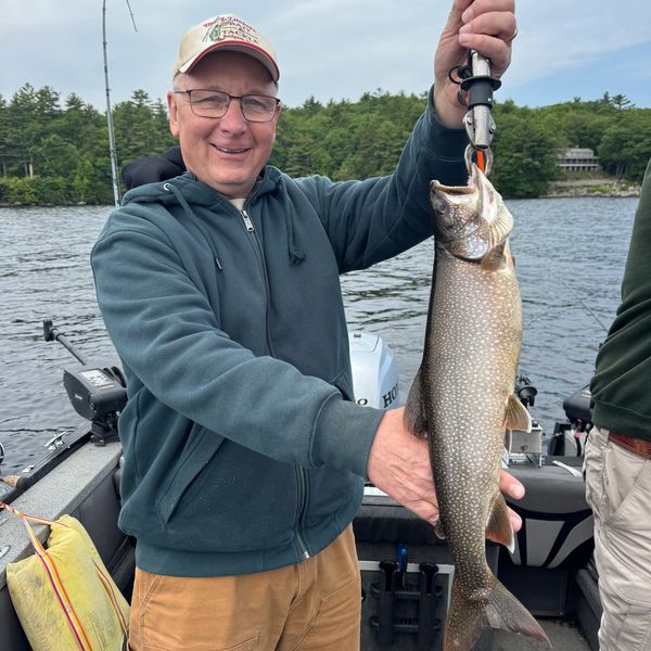 Man proudly holding a large fish on a boat.