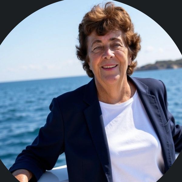 Smiling woman in navy blazer on a boat with ocean background.