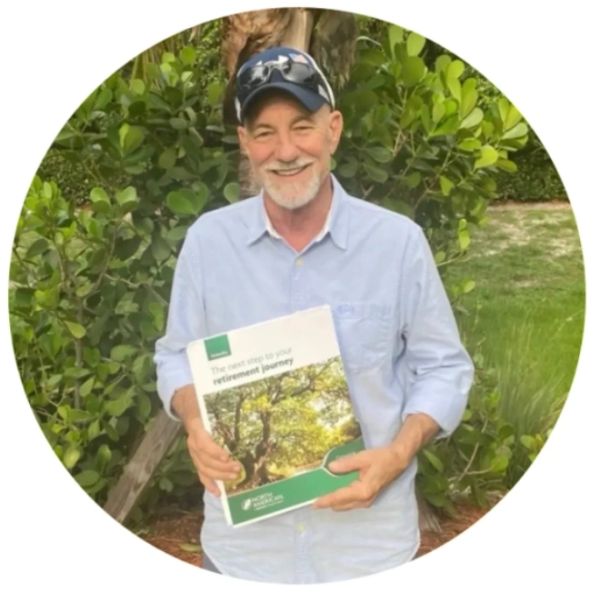 Smiling man holding a retirement guide outdoors.