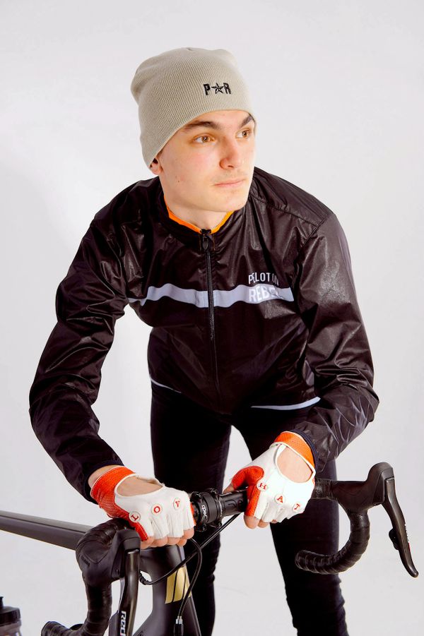A model is wearing a black long sleeved Peloton Rebel waterproof cycling jacket 