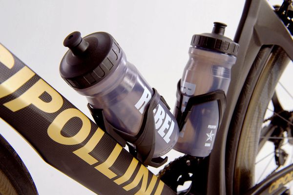 Two custom Peloton Rebel water bottles sit in bottle cages upon a Cipollini road bike. 