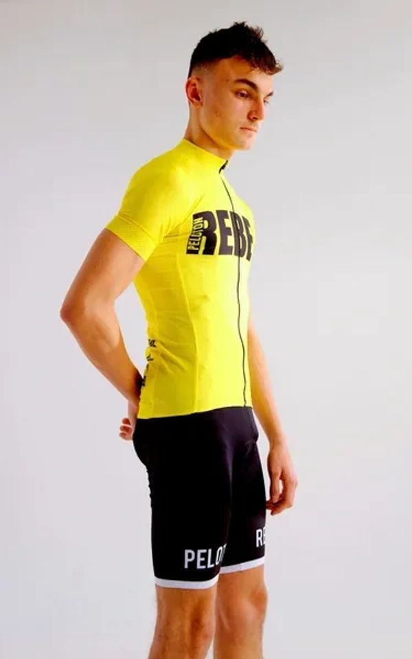 A model is pictured wearing a yellow and black Peloton Rebel jersey along with Peloton Rebel shorts