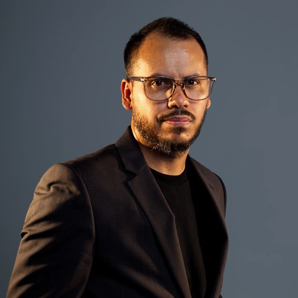 Man with glasses wearing a black suit jacket.