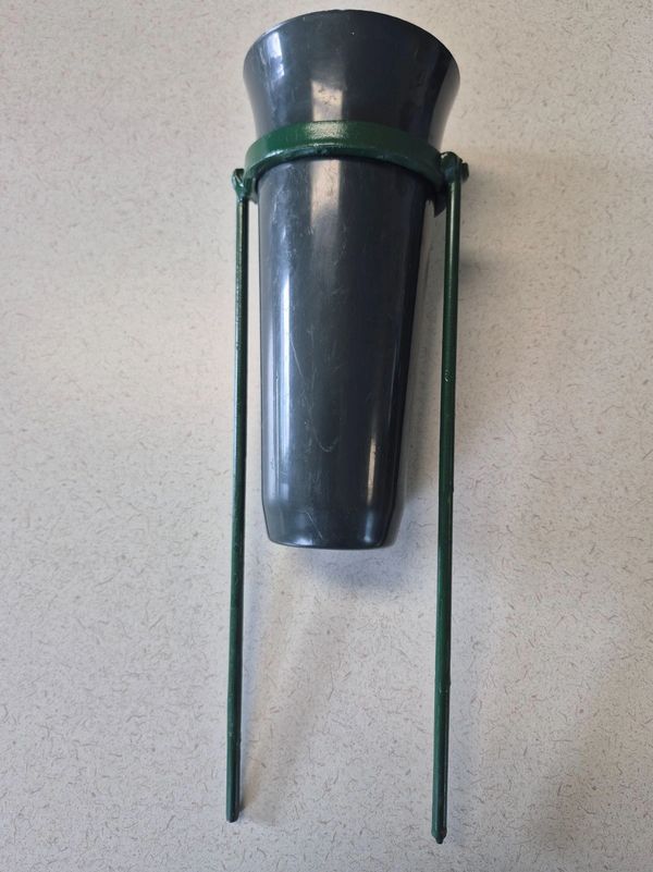 Black plastic garden planter holder with green stakes.
