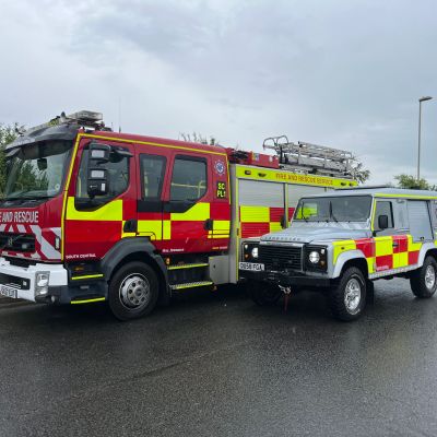Fire and rescue vehicles parked on a wet road.