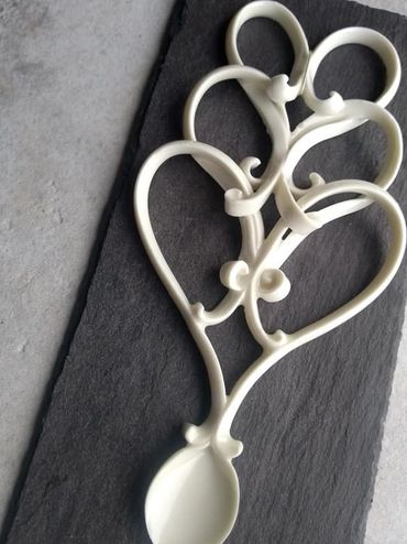 White heart-shaped utensil with a spoon on a dark surface.