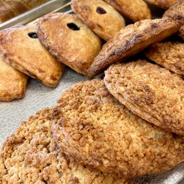 Close-up of crumbly cookies and hand pies on a baking tray.