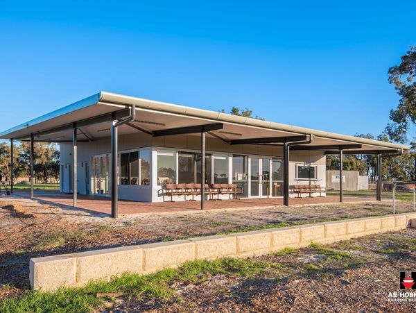 Modern building with large windows and an extended roof in a sunny outdoor setting.