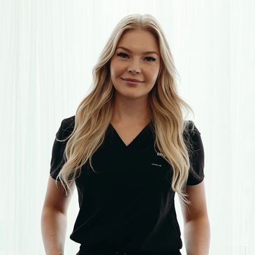 Smiling woman with long blonde hair in a black scrub top.