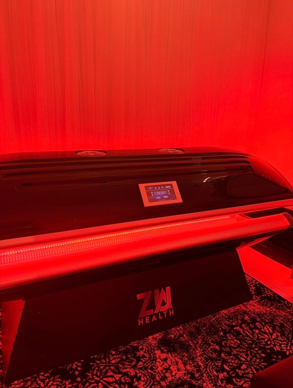 A sleek black health device glowing red in a dimly lit room.