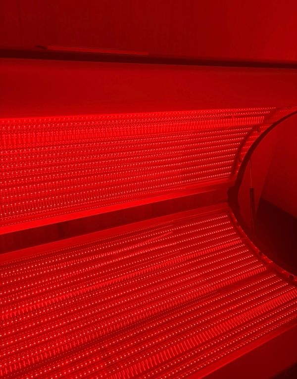 Red LED light therapy bed glowing intensely.