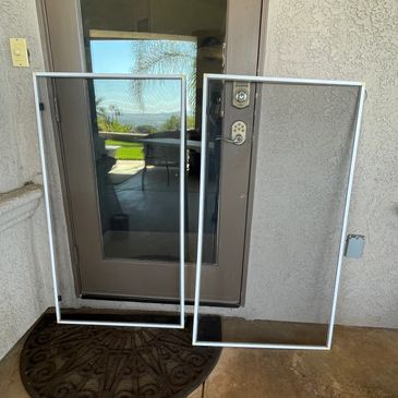 Two large rectangular glass panels leaning against a closed door outside a house.