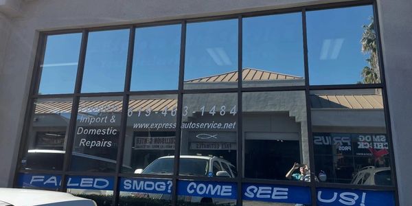Reflection of a car and repair shop signage in glass windows.