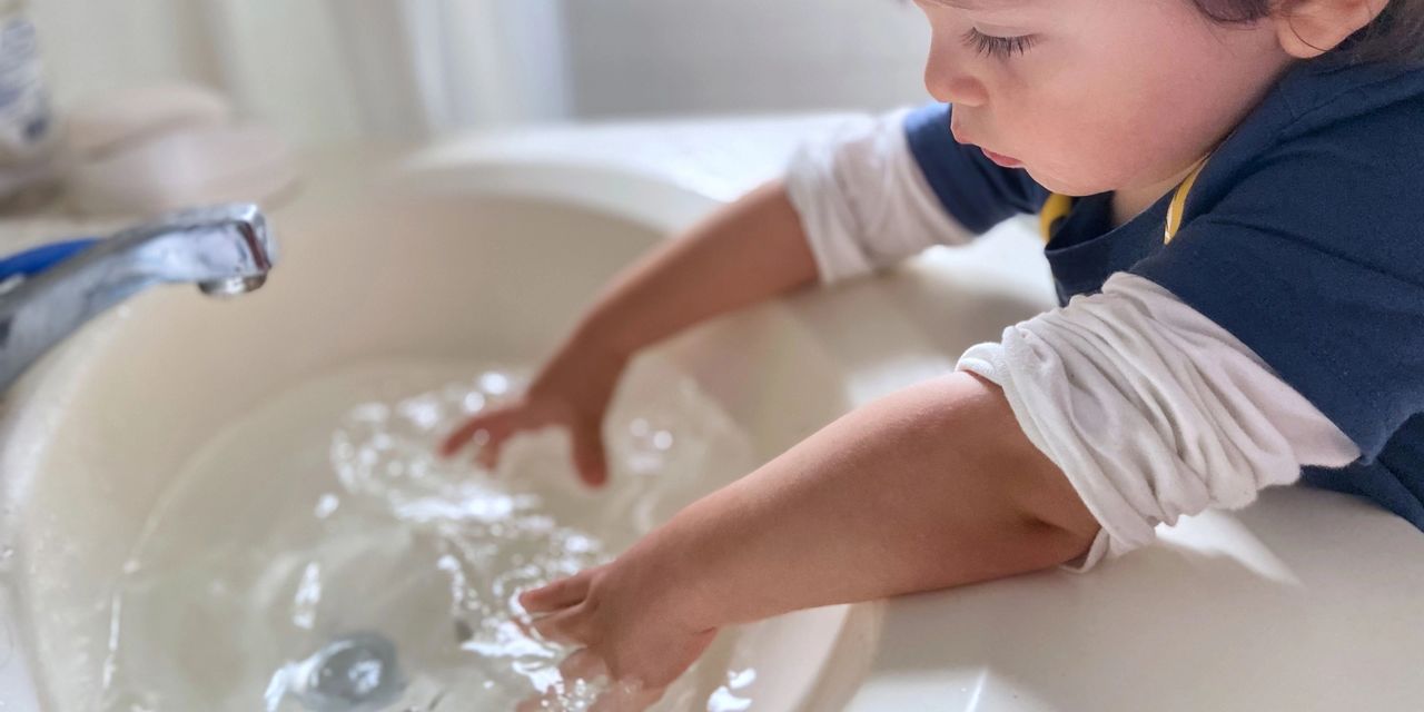 Child playing in sink filled with water