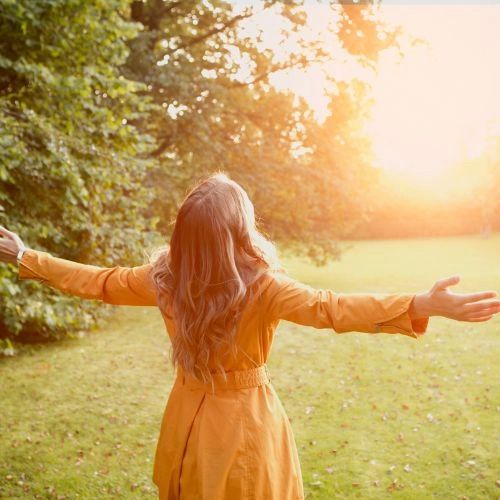 Woman facing the sun with her arms open
