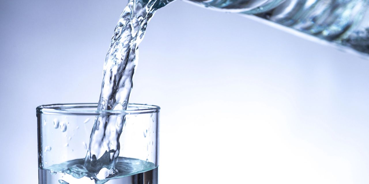A clear pitcher of water being poured into a clear glass