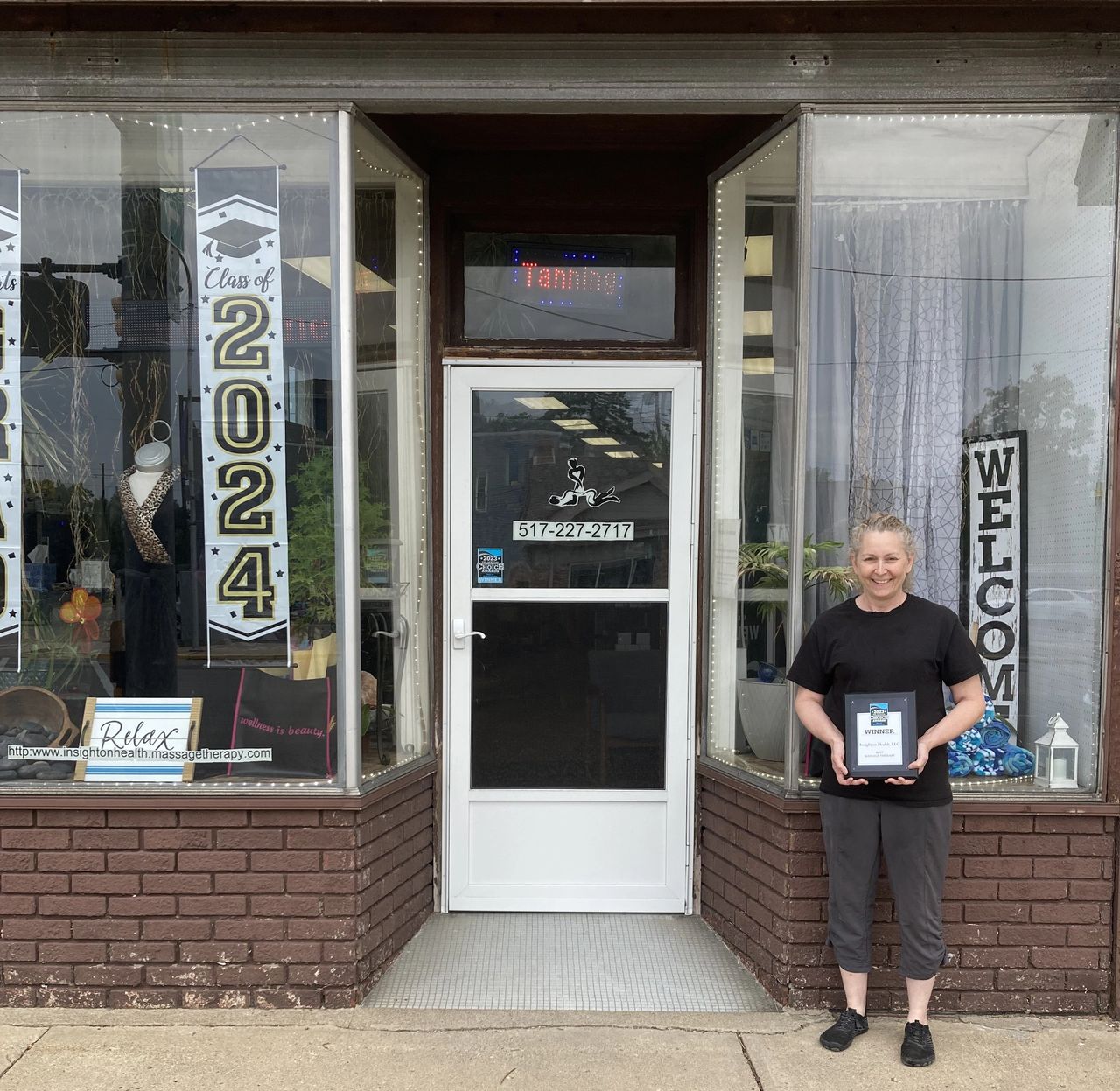 Catina standing outside her business, holding her Community Choice Award