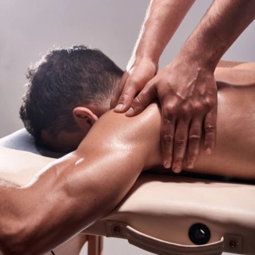 A client lying face down on a massage table, receiving a shoulder massage. 