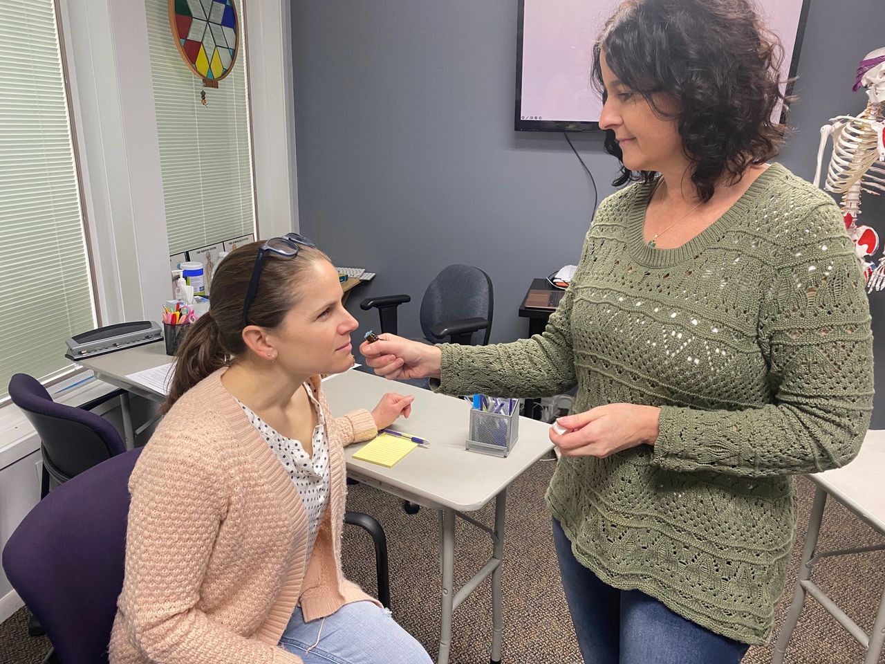 Seva holding a bottle of essential oil to a workshop participants nose, while explaining its properties and uses.