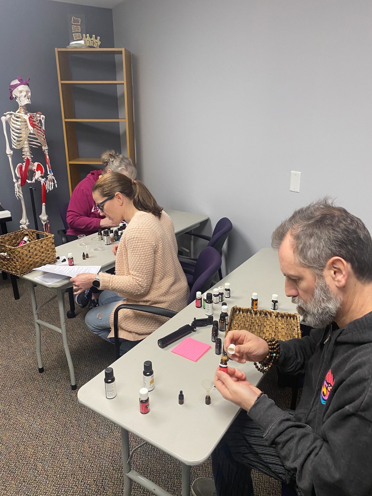 Workshop participants sitting at tables filled with bottles of essential oils and learning about various essential oils