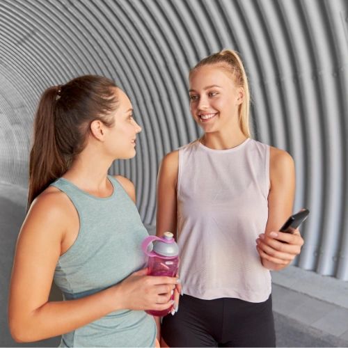 Two female hydration buddies using a mobile app and comparing their water consumption 