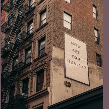 A simple poster on a brick wall asking the question "How are you really?"