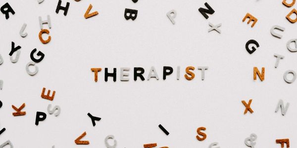 A single word 'Therapist' spelt out brown, black and white letters amongst other individual letters.
