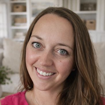 Smiling woman with long brown hair in a cozy living room.