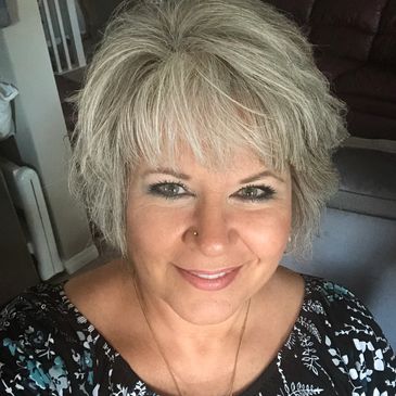 Smiling woman with short gray hair and nose piercing.