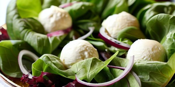 Salada de folhas verdes, cebola roxa e bolinhas de queijo de cabra