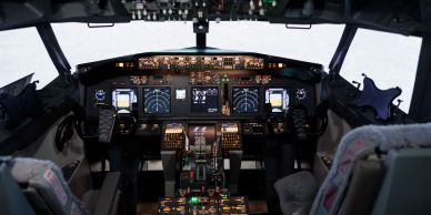 Inside view of an airplane cockpit with lit instruments.