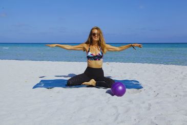 woman doing mat pilates on the beach mermaid pose