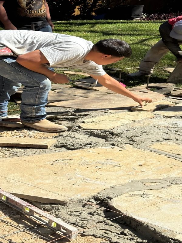Workers installing stone pavement outdoors on a sunny day.