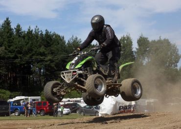 Person jumping a quad bike off a dirt ramp.