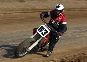 Motorcyclist racing on dirt track.
