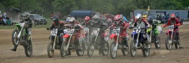 Dirt bike race with multiple riders at start line.