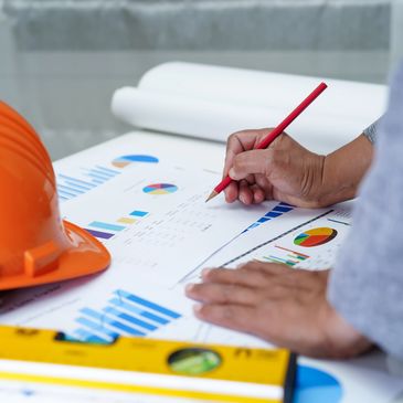 Men's hands on chart paper with a hard hat
