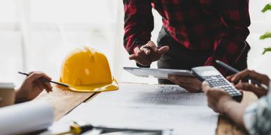 Image of 3 human figures working on paperwork at a construction site