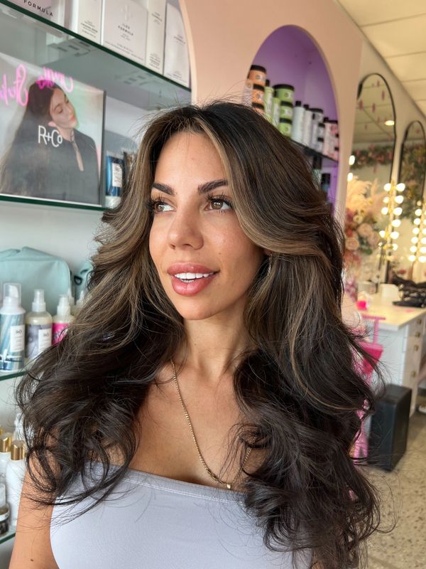 Woman with voluminous, styled hair posing in a beauty salon.