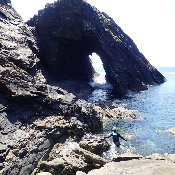 Walking towards a large sea arch while coasteering