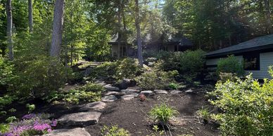 Large backyard with stone steps, mulch beds, and pretty flowers.