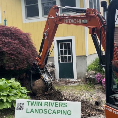 Hitachi excavator being used to move boulders and large rocks during hardscape project