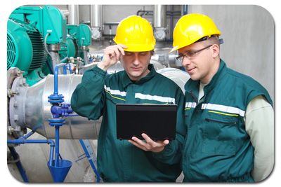 Industrial workers reviewing training material on a laptop.