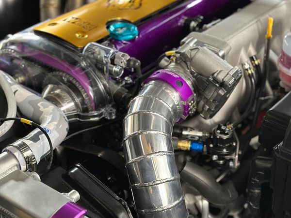 Close-up of a customized turbocharged engine with purple and gold components.