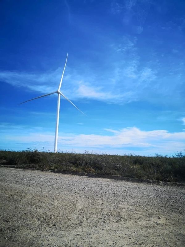 A solitary wind turbine stands against a bright blue sky.